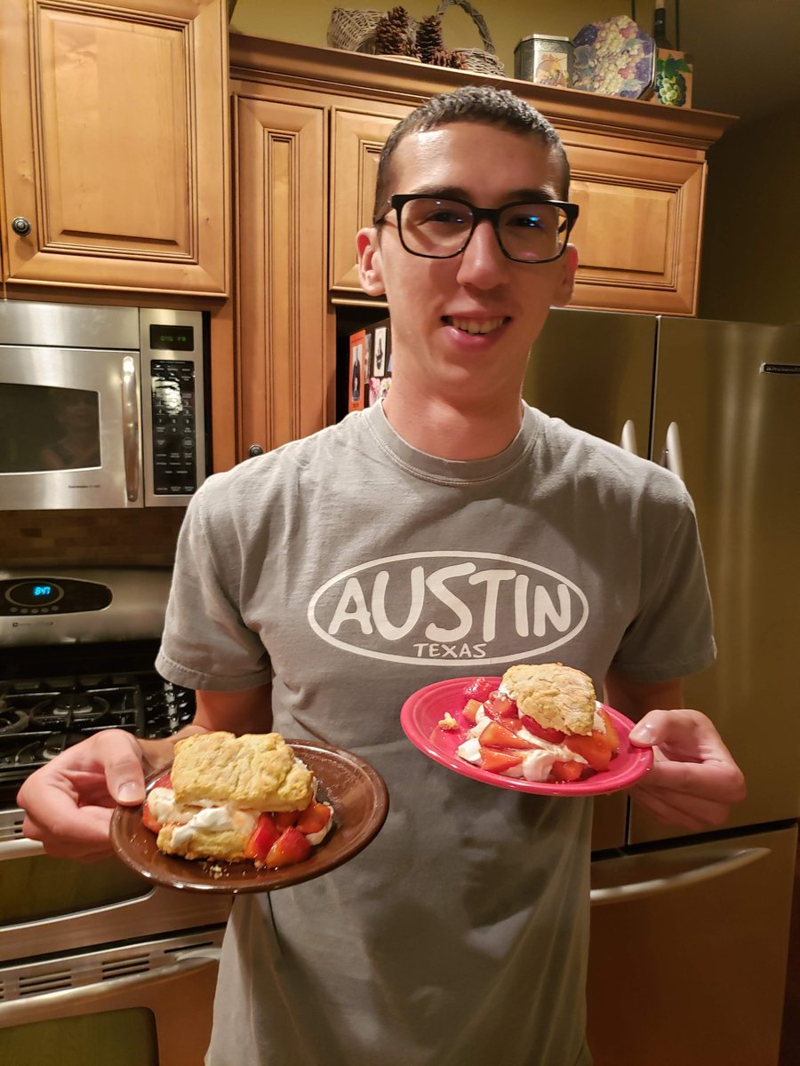 Alex smiling in the kitchen while holding two strawberry desserts
