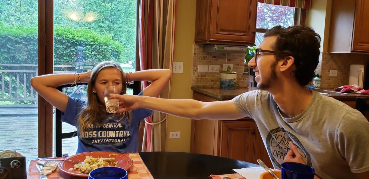 Alex sharing a playful moment with a family member at the dining table