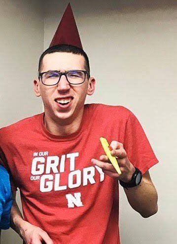 Alex smiling in a red Nebraska shirt and party hat